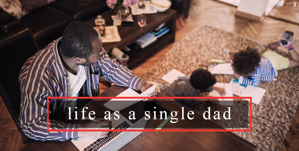 Black Single Dad working with 2 kids on living room floor